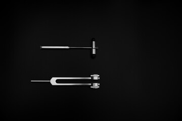 tuning fork C 128 on a black background with gradation and otorhinoscope and neurological hammer