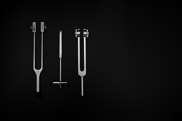 tuning fork C 128 on a black background with gradation and otorhinoscope and neurological hammer