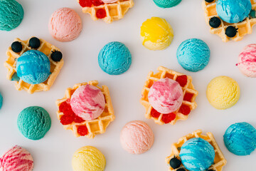 Colorful pattern with waffles, ice cream scoops, raspberries and fresh blueberries on white background. Sweet food concept. Perfect for summer themed designs and playful backdrops. Flat lay style.