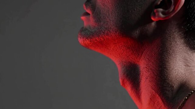 Close-up of man&rsquo;s neck with red light indicating throat pain or inflammation, sore throat medical concept