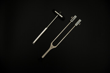 tuning fork C 128 on a black background with gradation and otorhinoscope and neurological hammer