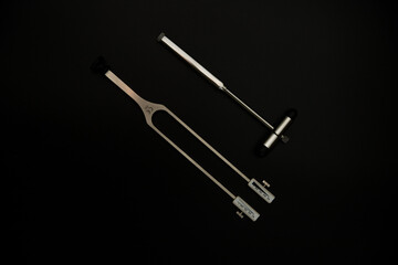 tuning fork C 128 on a black background with gradation and otorhinoscope and neurological hammer