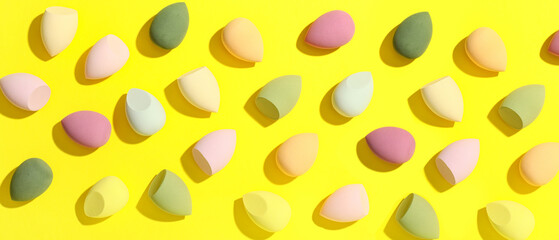 Colorful makeup sponges on yellow background