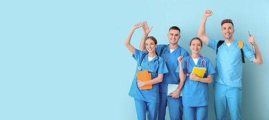 Group of happy medical students on light blue background with space for text