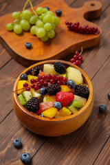 Bowl of fresh fruit salad on wooden background