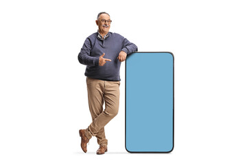 Full length portrait of a mature man pointing at a big smartphone with blue screen