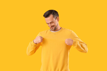 Young man in sweatshirt on yellow background