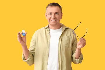 Mature man with contact lens case and eyeglasses on yellow background