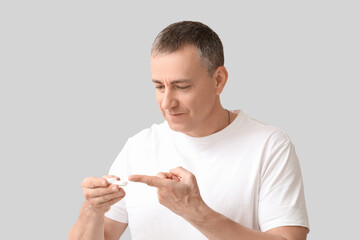 Mature man with contact lens and case on grey background