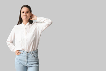 Beautiful young woman in stylish jeans on grey background