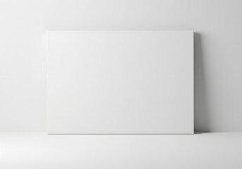 Fototapeta premium Clean empty white rectangular canvas leaning against a bright white wall with subtle soft shadows on a minimalist background, concept for product display, graphic design presentation and branding