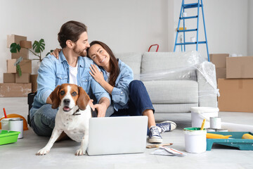 Young couple with Beagle dog and laptop during repair in their new house