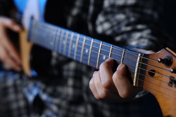 Obraz premium Woman playing guitar on dark background, closeup