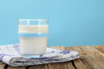 Fresh milk in glass on wooden table against light blue background, closeup. Space for text