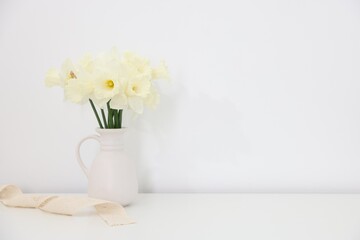Beautiful daffodils in vase on white table at home, space for text