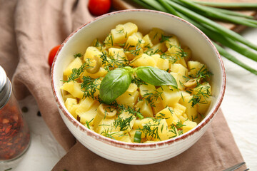 Bowl of tasty potato salad with olives and basil on white background