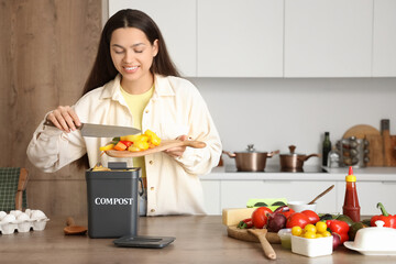 Young woman throwing food into container for compost in kitchen