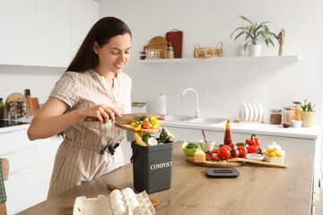 Young woman throwing food into container for compost in kitchen