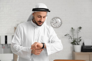 Arab businessman looking at wristwatch in office