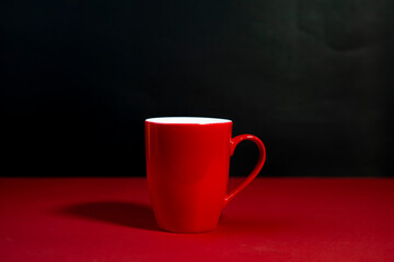 Bold Red Ceramic Tea Mug with Handle in White Studio Light  isolated on Black and Red background