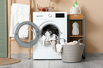 Basket with dirty clothes near washing machine in laundry room