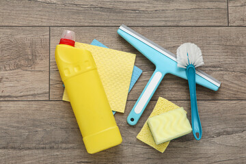 Bottle of detergent with rags, sponges, scraper and cleaning brush on laminate background