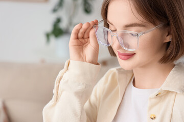 Beautiful young happy woman in new eyeglasses at home