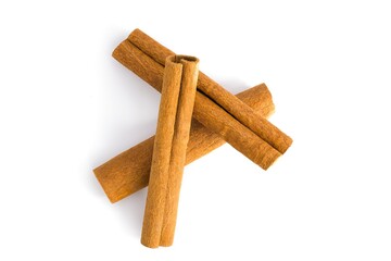 Cinnamon bark pieces spread across a white surface, highlighting their fibrous texture and earthy hues.