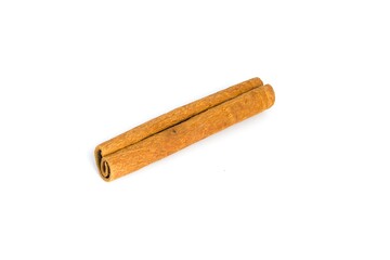 Neatly arranged cinnamon bark fragments on a white surface, focusing on their coarse texture and warm tones.