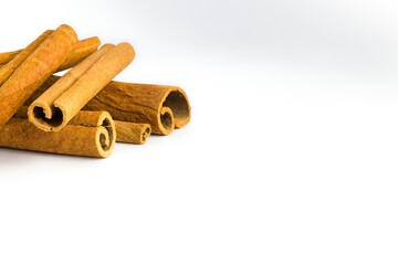 Dried cinnamon bark pieces arranged on a white background, showcasing their rich brown tones and textured surfaces.