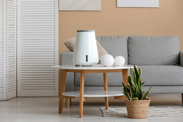 Air humidifier on table and plant in living room interior