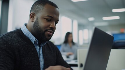 Fototapeta premium A focused professional working on a laptop in a modern office environment