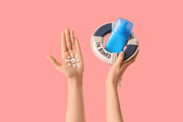 Woman holding lifebuoy ring with sun made of sunscreen cream on her hand against pink background