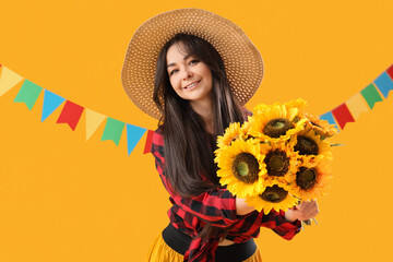 Young happy woman in straw hat with bouquet of sunflowers and flags on yellow background. Festa...