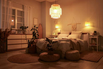 Interior of bedroom with surfboard, glowing lamps and plants at night