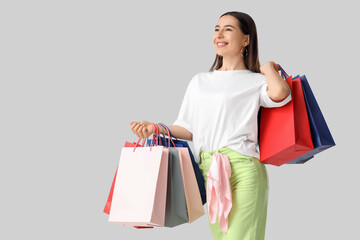 Happy young woman with shopping bags on white background
