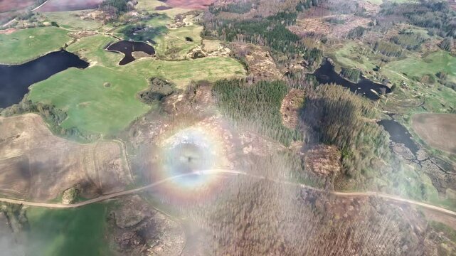 Drone view above rural European landscape with scattered lakes, forests, fields, and light clouds