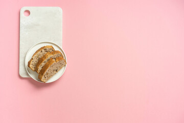 Nut cake with jam on white plate and pink background.