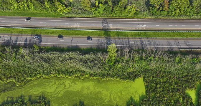 Daytime aerial hyperlapse video over a stretch of interstate, highway, through a green vegetative area. 