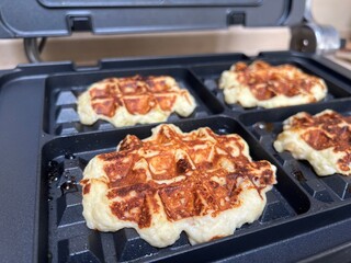 Golden waffles are baking in  waffle maker for breakfast or brunch evoking cozy weekend breakfasts and comforting family moments, perfect for food blogs, recipe sites, or advertising breakfast product