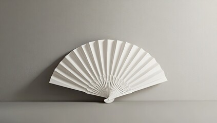 Elegant white fan resting on a plain surface