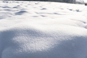 Soft white snowdrift surface sparkling under low winter sunlight in closeup