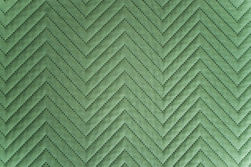 Close-up of quilted green fabric with zigzag stitched pattern in soft lighting