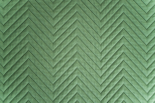 Close-up of quilted green fabric with zigzag stitched pattern in soft lighting
