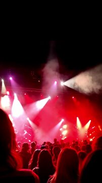 A crowd is in the audience of a music bank concert with shining red lights above the stage. Generated with AI