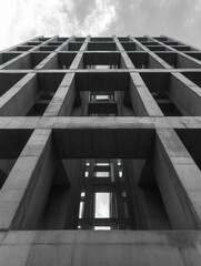 Abstract view of a large concrete building structure with repetitive square frames and open spaces, showcasing geometric patterns and an industrial atmosphere