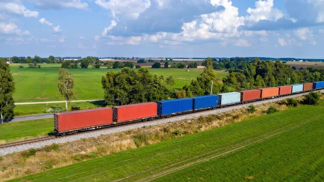 Freight train passing through scenic countryside, containers loaded with export goods, moving towards global markets



