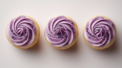 Fototapeta premium Three cupcakes with swirls of purple frosting