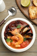 Delicious seafood soup served on wooden table, flat lay