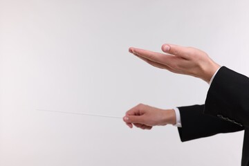 Conductor with baton on light grey background, closeup. Space for text